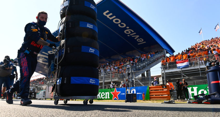 Een lid van Red Bull loopt met banden en bandenwarmers over de grid.